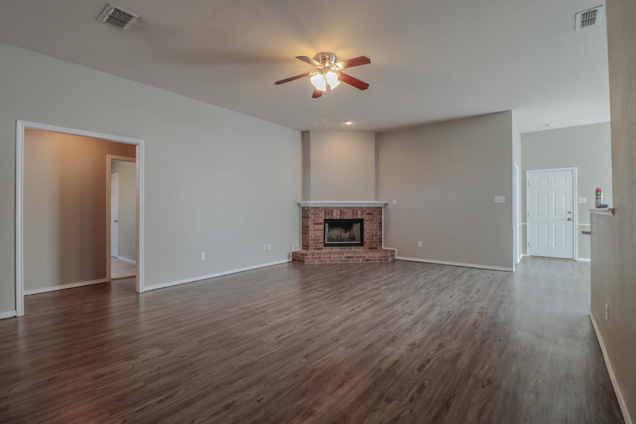6808 88th Street Lubbock, TX 79424 - Photo 8 of 17 a view of an empty room with wooden floor and a ceiling fan