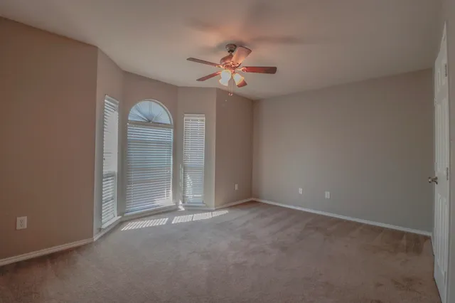 an empty room with closet and a ceiling fan