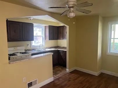 a kitchen with a sink a stove cabinets and wooden floor