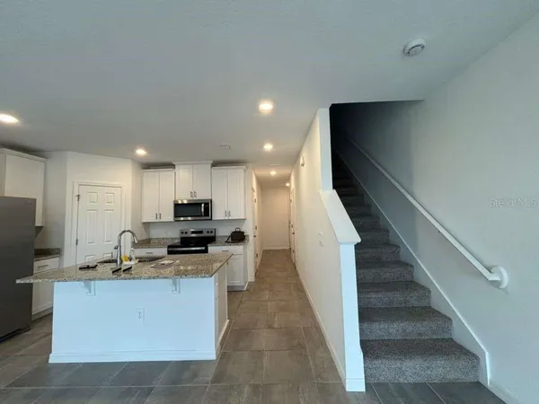 a kitchen with stainless steel appliances kitchen island granite countertop a stove a sink and a refrigerator