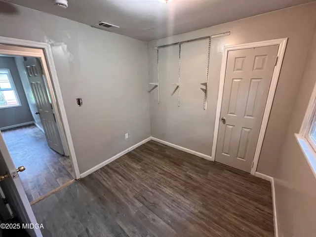 an empty room with wooden floor and entrance