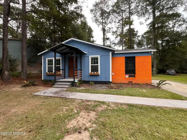 a view of a house with a yard and large tree