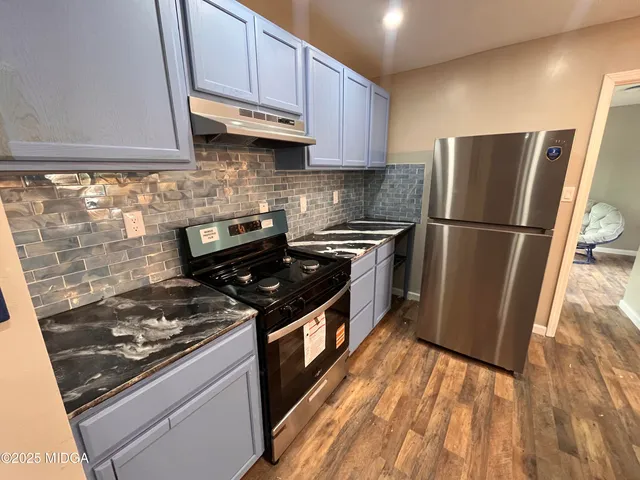 a kitchen with a sink a refrigerator and a stove top oven