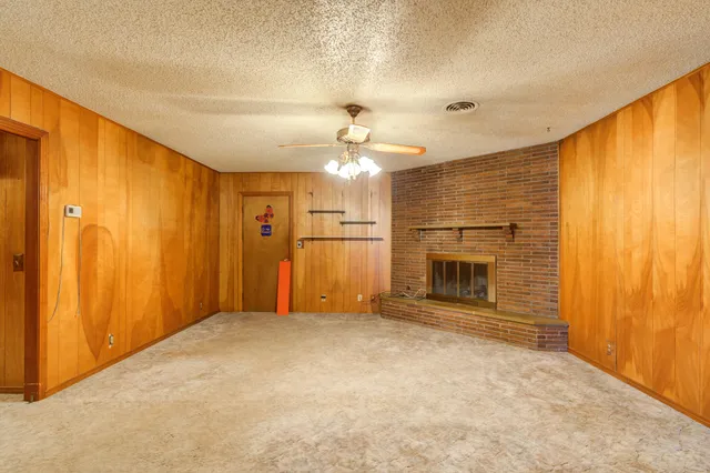 a view of an empty room with window and chandelier fan