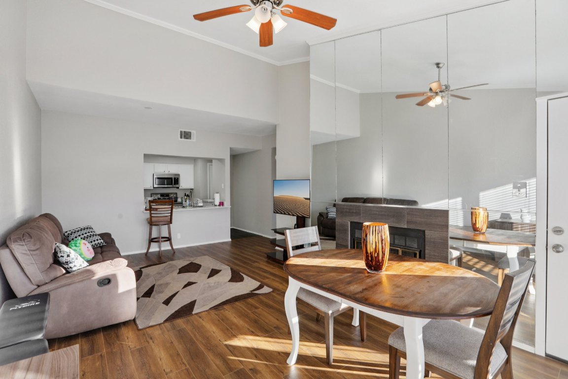 807 West 25th Street, Unit 302 Austin, TX 78705 - Photo 7 of 18 Dining space with ceiling fan, ornamental molding, dark wood finished floors, a fireplace, and a high ceiling