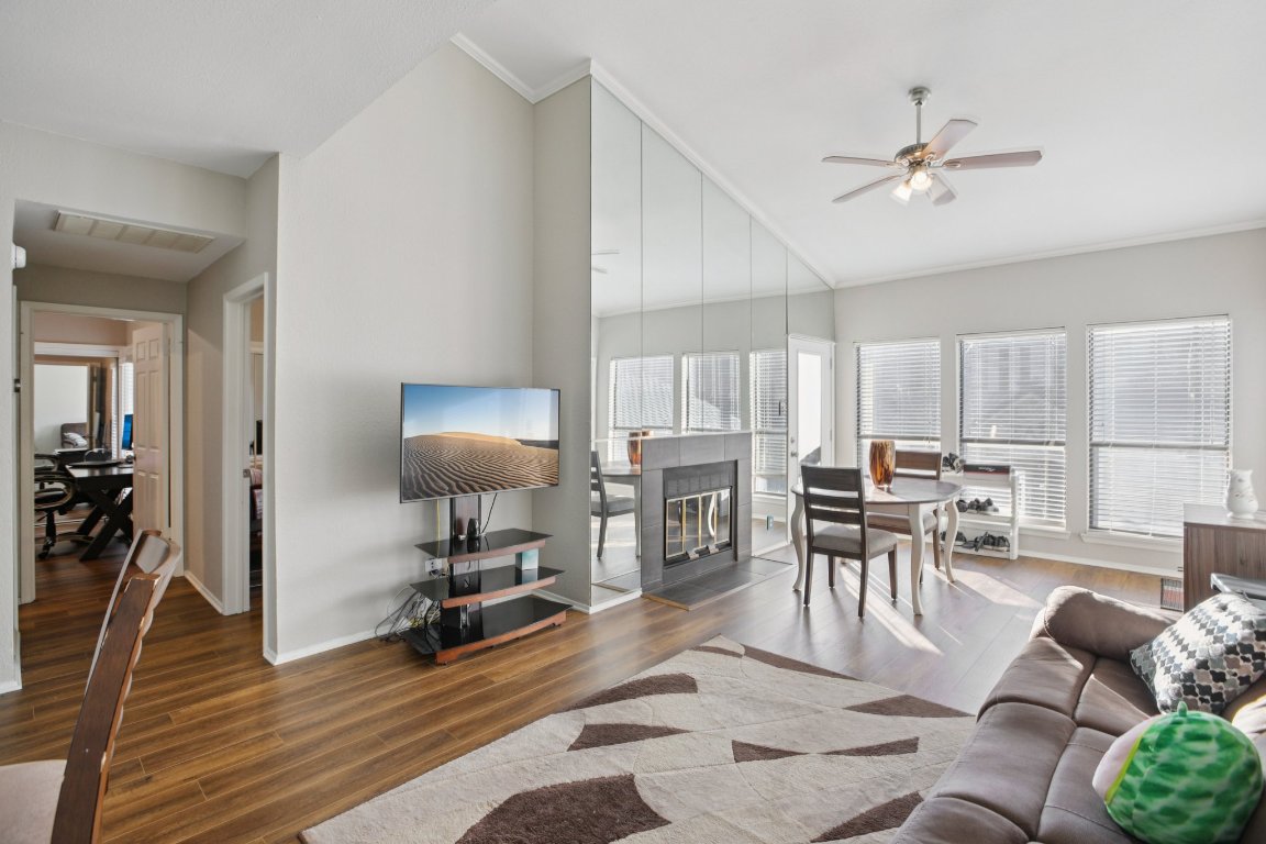 807 West 25th Street, Unit 302 Austin, TX 78705 - Photo 9 of 18 Living room featuring wood finished floors, a fireplace with flush hearth, crown molding, and a ceiling fan