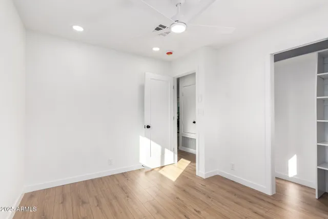 an empty room with wooden floor and ceiling fan