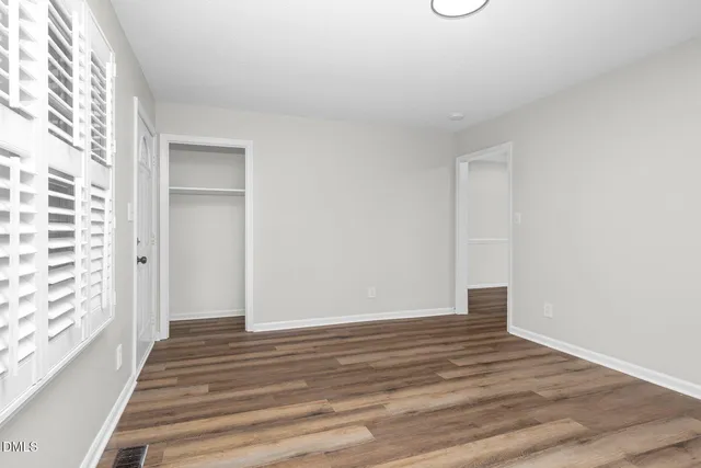 a view of an empty room with wooden floor and a window