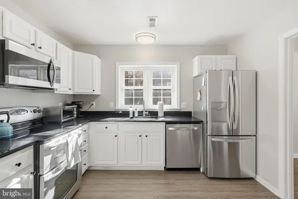 a kitchen with granite countertop a refrigerator sink and cabinets