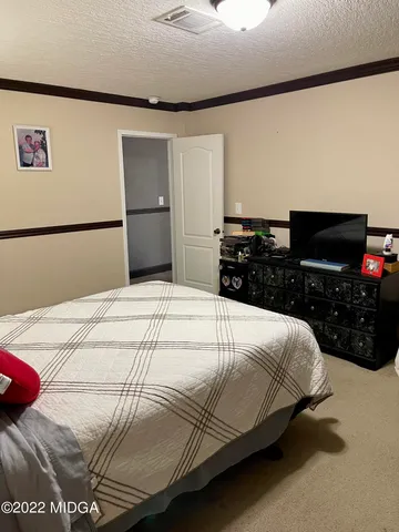 a bedroom with a bed and a view of kitchen