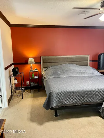 a bedroom with a bed chair and wall painting