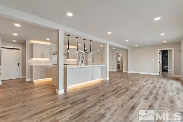 a view of a big room with wooden floor and a kitchen
