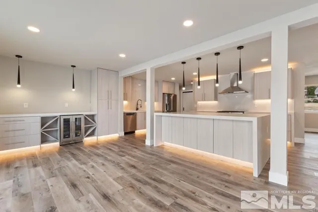 a large kitchen with stainless steel appliances kitchen island a large counter top and wooden floors