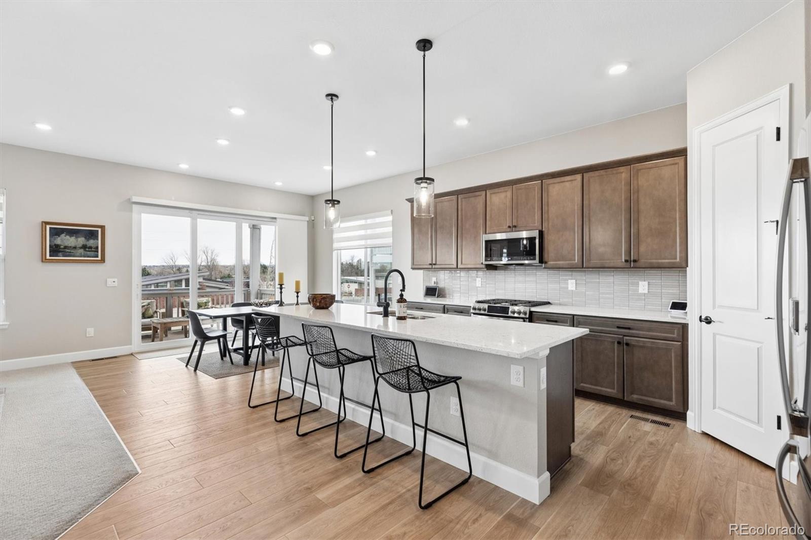 5980 South Platte Canyon Road Littleton, CO 80123 - Photo 11 of 50 a kitchen with stainless steel appliances granite countertop a stove top oven a refrigerator a sink and a dining table with wooden floor
