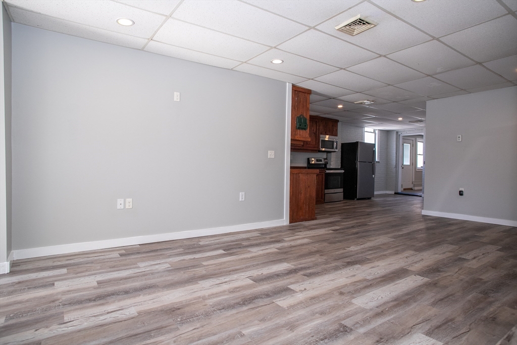 865 South Barre Road Barre, MA 01074 - Photo 17 of 34 an empty room with wooden floor and a kitchen