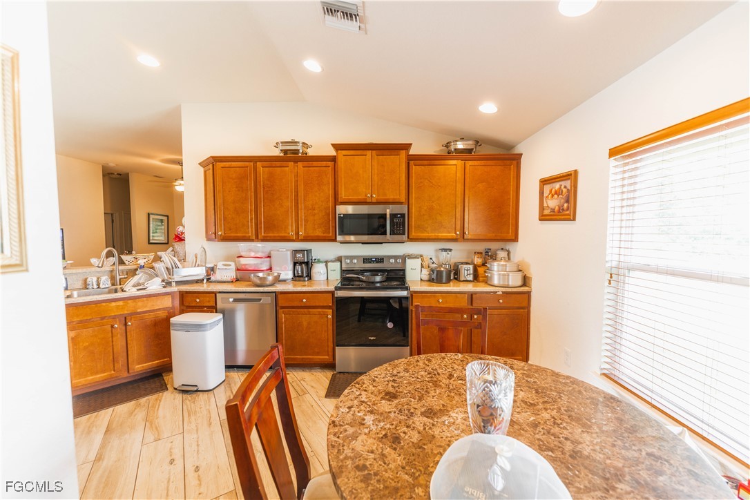 5134 Baron Street Lehigh Acres, FL 33971 - Photo 4 of 30 a kitchen with stainless steel appliances granite countertop a stove top oven a sink a dining table and chairs