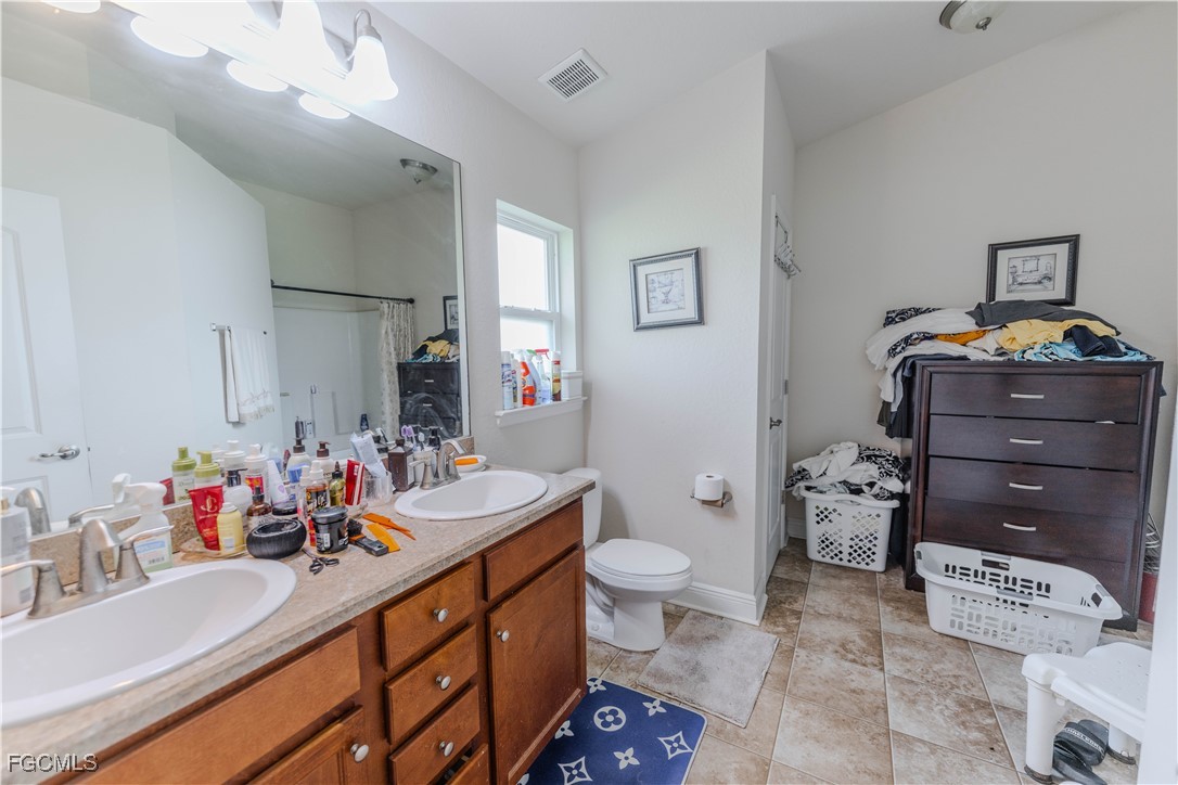 5134 Baron Street Lehigh Acres, FL 33971 - Photo 10 of 30 a bathroom with a sink vanity mirror and toilet