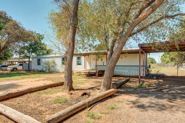a view of a house with wooden fence next to a yard