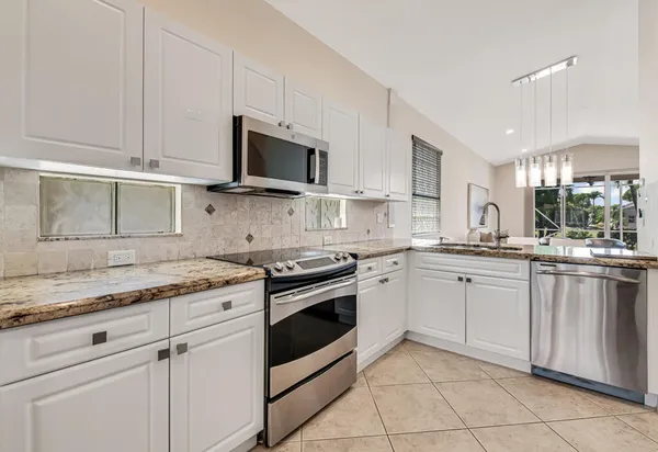a kitchen with stainless steel appliances granite countertop white cabinets a sink and dishwasher