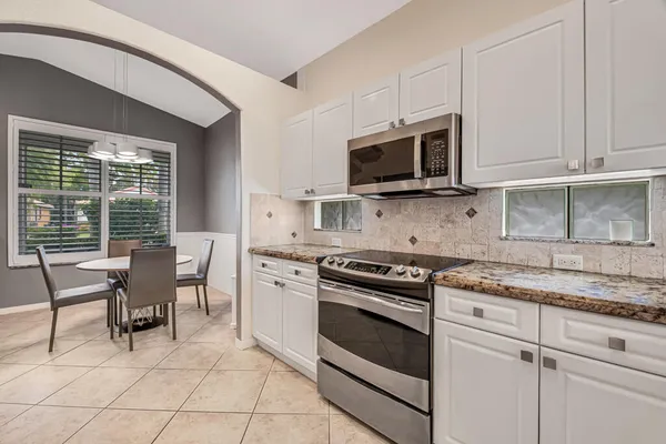 a kitchen with stainless steel appliances granite countertop a stove top oven a sink dishwasher a dining table and chairs with wooden floor