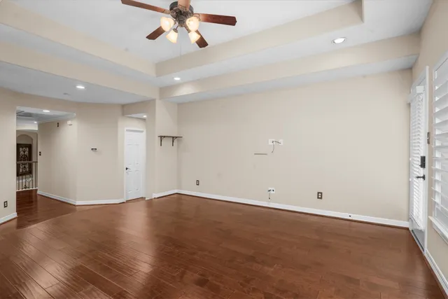 an empty room with wooden floor and ceiling fan