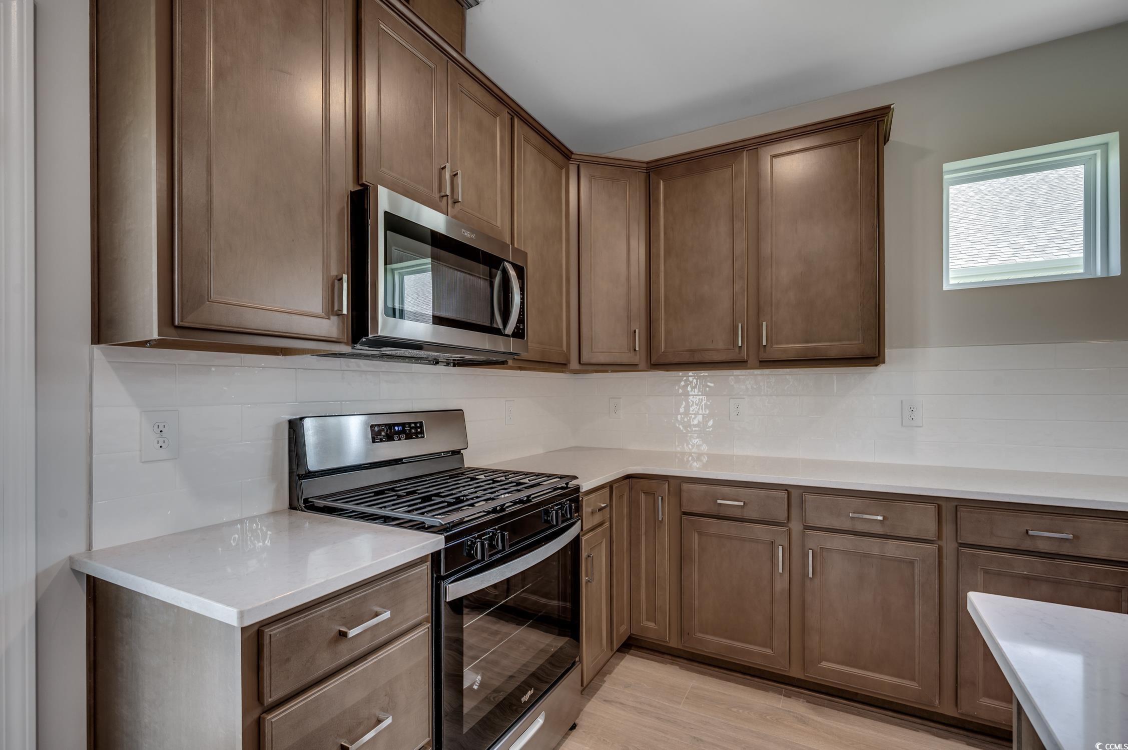 439 Kapalua Loop Little River, SC 29566 - Photo 12 of 36 Kitchen featuring stainless steel appliances, tasteful backsplash, light stone countertops, and light wood-style flooring