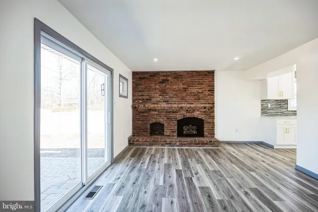 a view of a livingroom with a fireplace wooden floor and windows