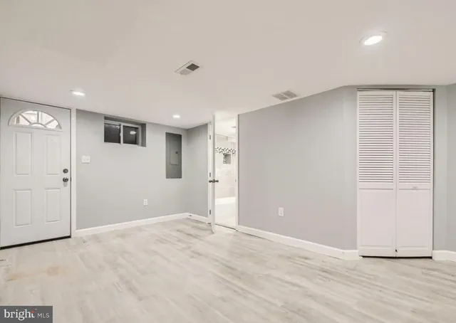 a view of an empty room with wooden floor and closet