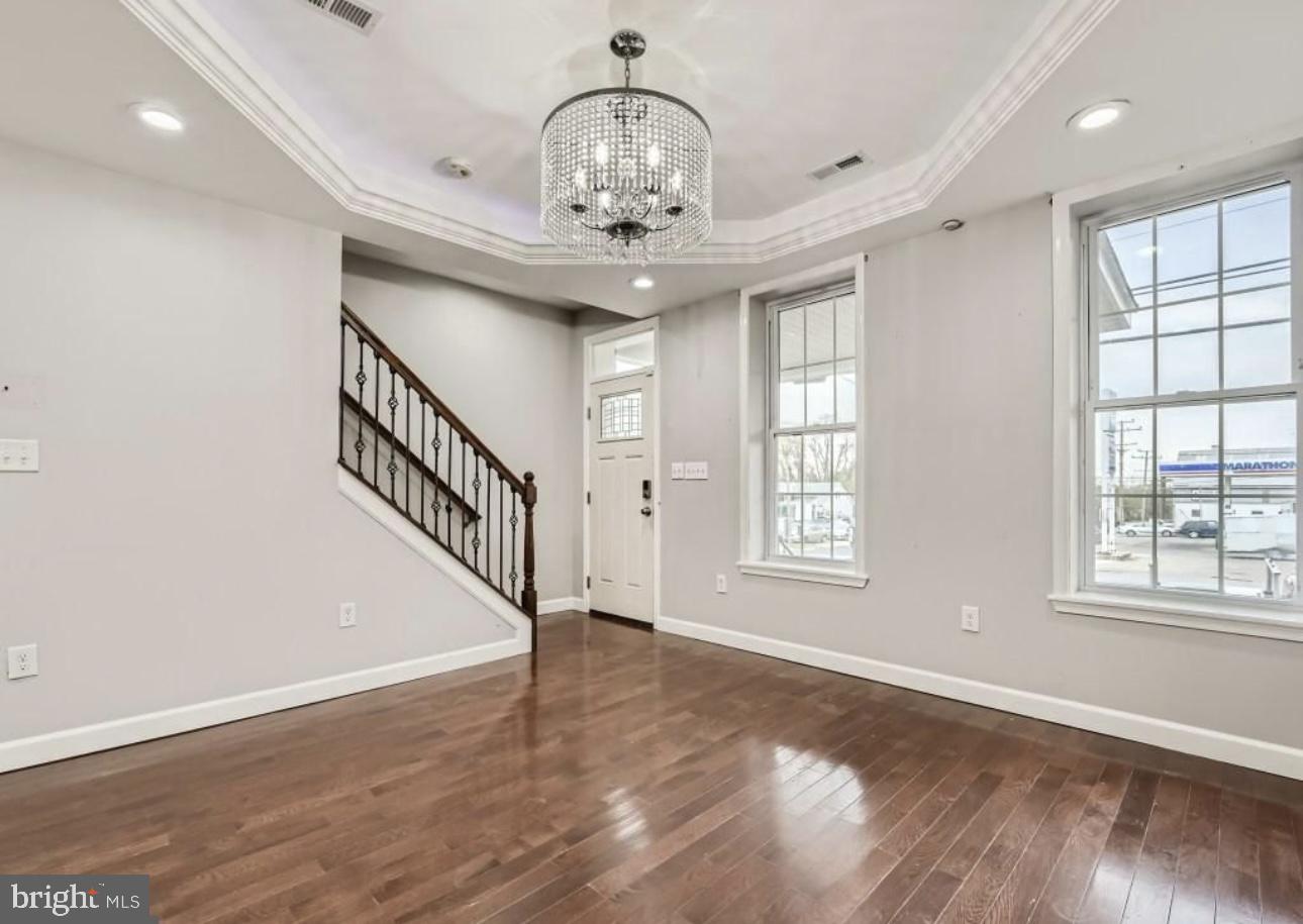 905 East Patapsco Avenue Baltimore, MD 21225 - Photo 5 of 25 a view of an empty room with wooden floor and a chandelier