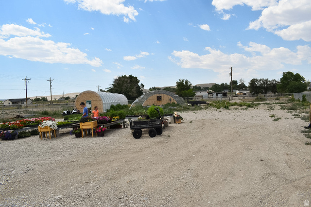 345 North Main Street Clawson, UT 84516 - Photo 13 of 17 Expansive gravel lot with multiple hoop houses, power poles, and distant structures, suitable for various agricultural or commercial uses