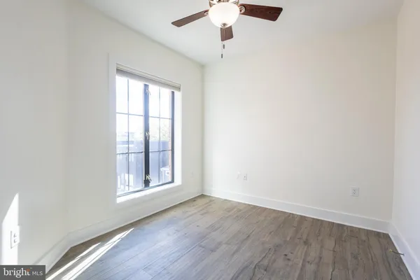 an empty room with wooden floor chandelier fan and windows