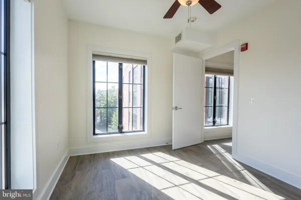 an empty room with chandelier fan and windows