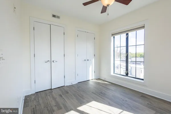 an empty room with wooden floor chandelier fan and windows