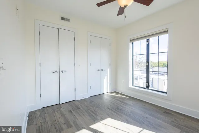 an empty room with wooden floor chandelier fan and windows