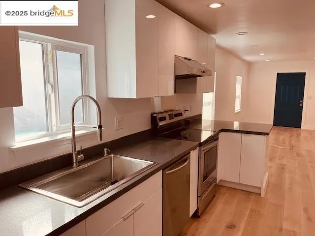 a kitchen with stainless steel appliances granite countertop a sink a stove and a refrigerator