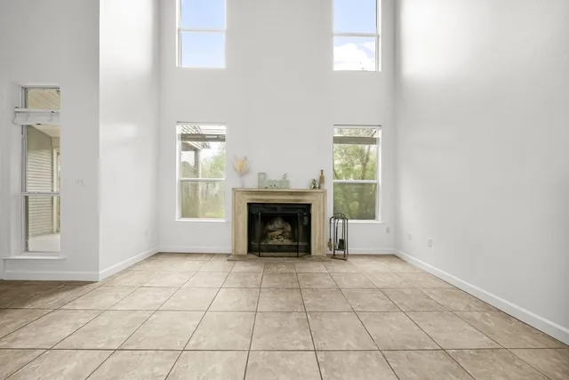 an empty room with windows and fireplace