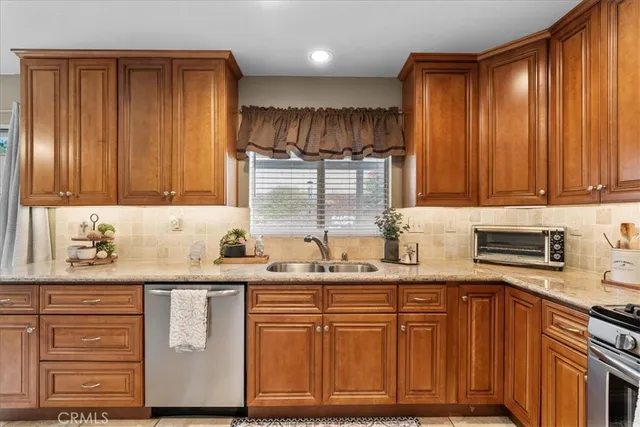 a kitchen with granite countertop stainless steel appliances a sink window and cabinets