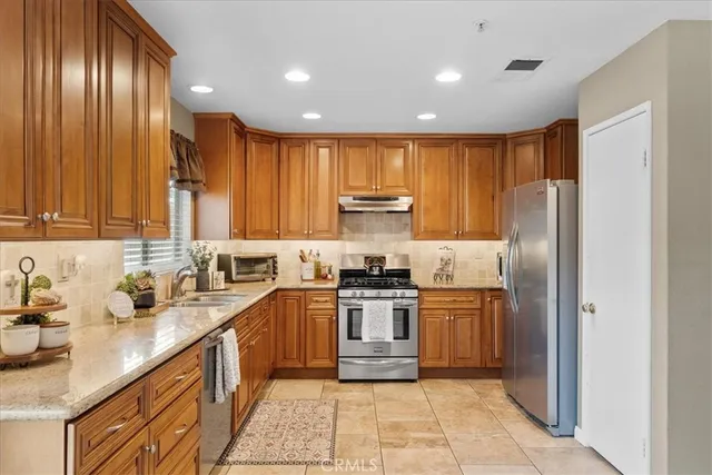 a kitchen with stainless steel appliances granite countertop a sink a stove a refrigerator and cabinets