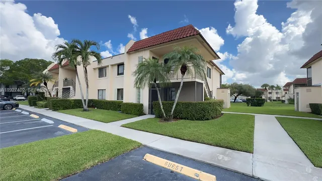 a view of a white house with a big yard and potted plants