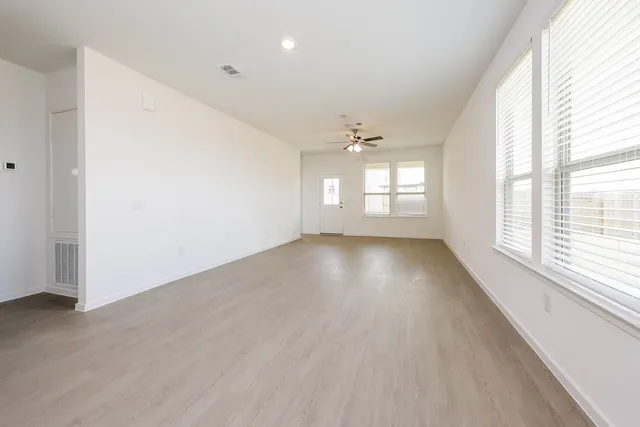an empty room with wooden floor and windows