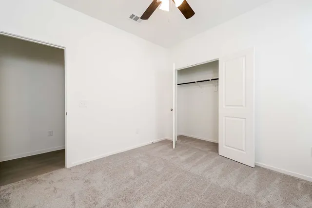 an empty room with closet and a ceiling fan