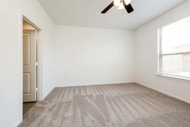 an empty room with ceiling fan and window