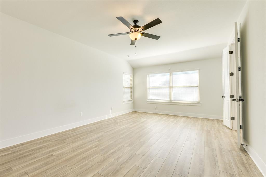 122 Biscayne Bay Bend Kyle, TX 78640 - Photo 13 of 29 an empty room with wooden floor a ceiling fan and windows