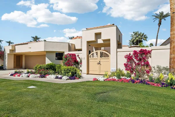 a front view of house and yard with beautiful flowers and green space