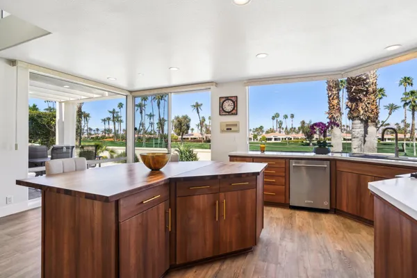 a kitchen with kitchen island granite countertop wooden floors and a view of living room