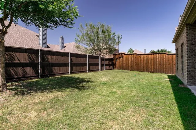 a view of a backyard with a large tree and wooden fence