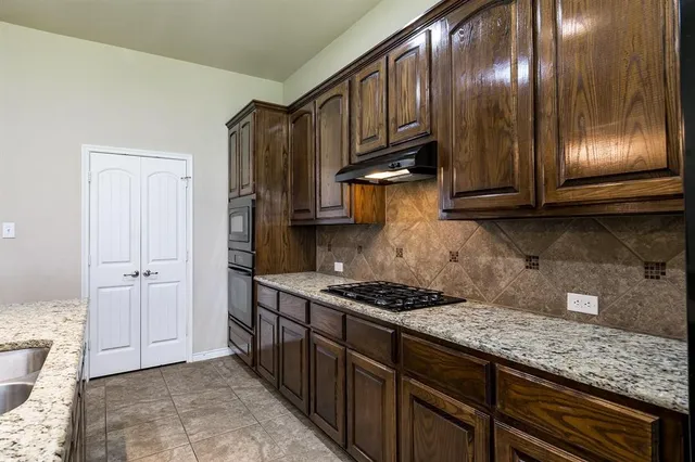 a kitchen with granite countertop stainless steel appliances a stove microwave and cabinets
