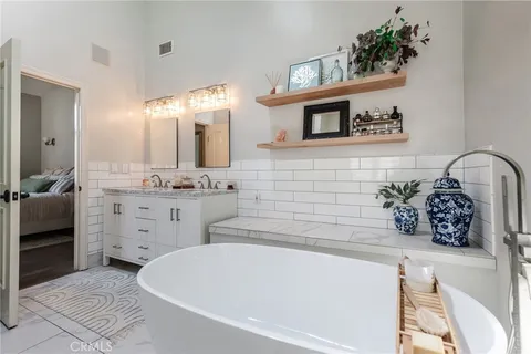 a bathroom with a double vanity sink a mirror and a bathtub