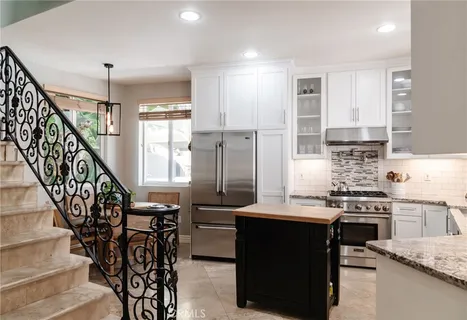 a kitchen with granite countertop a stove a sink and a refrigerator