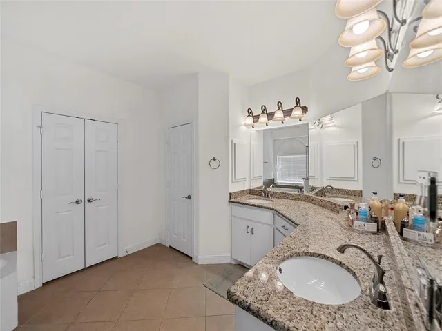 a en suite bathroom with a granite countertop tub shower and a sink